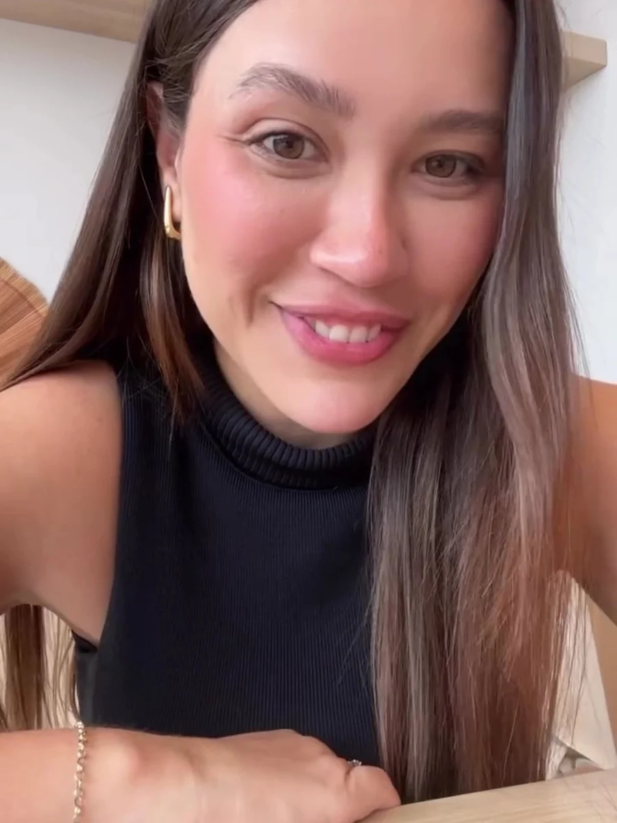 Dra. Natascha Dias sorrindo, de blusa preta de gola alta, em close no consultório